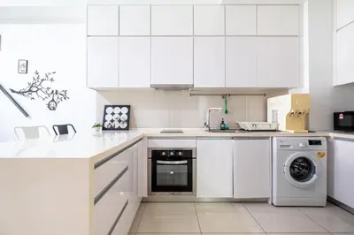 a white kitchen with white cabinets and a dishwasher at The Element Ampang in Kuala Lumpur