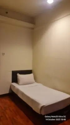 a bed in a room with a white wall at Regal Servies Suites at Times Square KL in Kuala Lumpur