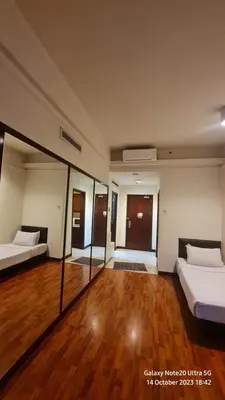 a large room with two beds and a wooden floor at Regal Servies Suites at Times Square KL in Kuala Lumpur
