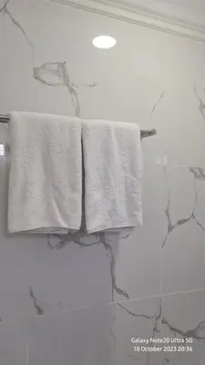 three towels hanging on a towel rack in a bathroom at Regal Servies Suites at Times Square KL in Kuala Lumpur