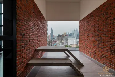 a bench against a brick wall with a view of the city at Chambers Signature Suites, Kuala Lumpur in Kuala Lumpur