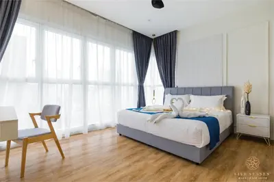 a bedroom with a bed and a chair and windows at Quill City Residences KLCC, Five Senses in Kuala Lumpur