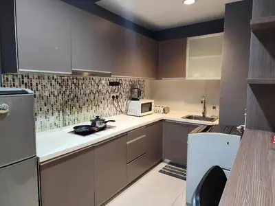 a kitchen with brown cabinets and a white appliance at Regalia Comfort Suites KLCC SkyPool in Kuala Lumpur