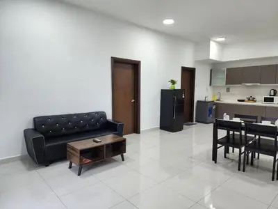 a living room with a black couch and a table at Regalia Comfort Suites KLCC SkyPool in Kuala Lumpur
