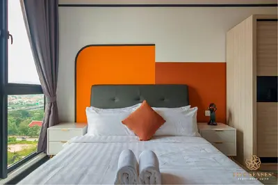 a bedroom with a bed with an orange wall at Neu Suites Signature Suites, KLCC in Kuala Lumpur