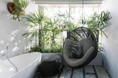 a wicker chair sitting in front of a window next to a tub at Lloyd's Inn Kuala Lumpur in Kuala Lumpur