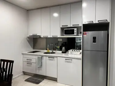 a kitchen with white cabinets and a stainless steel refrigerator at Summer Suits Klcc by KL Residence in Kuala Lumpur