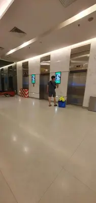 a man standing in a hallway with a room with two televisions at Summer Suits Klcc by KL Residence in Kuala Lumpur