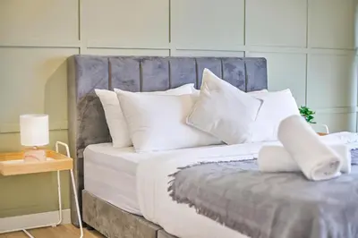 a bed with white pillows and a blue headboard at Continew Residence TRX KL in Kuala Lumpur