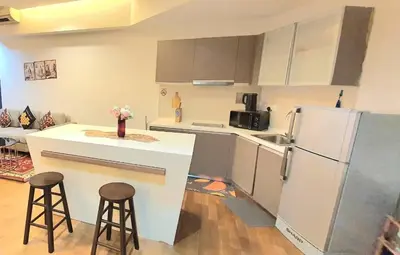 a kitchen with a refrigerator and two bar stools at Regalia Suites with Infinity Pool KLCC by Staycation Homes in Kuala Lumpur