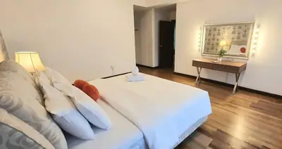 a bedroom with a white bed and a table at Regalia Suites with Infinity Pool KLCC by Staycation Homes in Kuala Lumpur