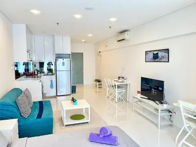 a living room with a blue couch and a kitchen at Summer suites KLCC by cozy stay in Kuala Lumpur