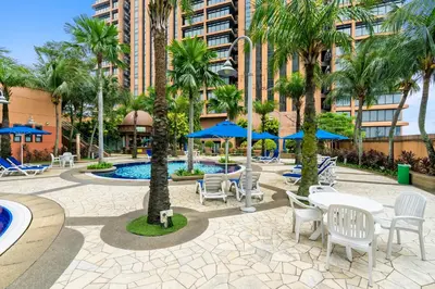 a patio with tables and chairs and palm trees at Suites at TimesSquare by Plush in Kuala Lumpur