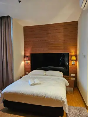 a bedroom with a large bed with a wooden headboard at Deluxe Family, Dua Sentral in Kuala Lumpur
