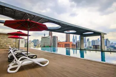a rooftop pool with chairs and umbrellas on a building at Cozy Suites @ D’majestic Place, KL City Centre in Kuala Lumpur