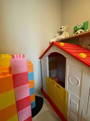 a toy house with a teddy bear sitting on a shelf at Kids Friendly Kuala Lumpur Apartment in Kuala Lumpur