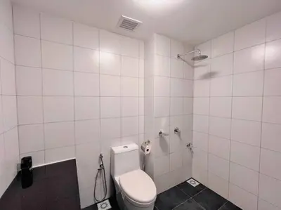 a white tiled bathroom with a toilet and a shower at KLCC View with Balcony @ Chambers, KL Near LRT PWTC & Sunway Putra Mall in Kuala Lumpur