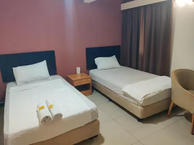 a hotel room with two beds and a chair at Hotel WKL in Kuala Lumpur