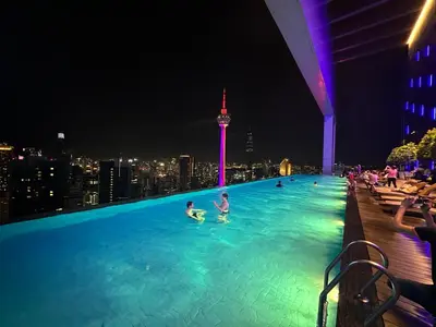 a swimming pool with people in the city at night at Platinum suites by BLUE SKY in Kuala Lumpur