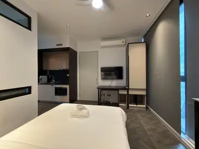 a bedroom with a white bed and a kitchen at Scarletz Suites KLCC Kuala Lumpur by OKIDOKI Homes in Kuala Lumpur