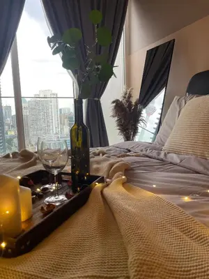 a bed with a tray with candles and wine glasses at Quill Residence Premium Cozy Suite By Ares Homestay in Kuala Lumpur