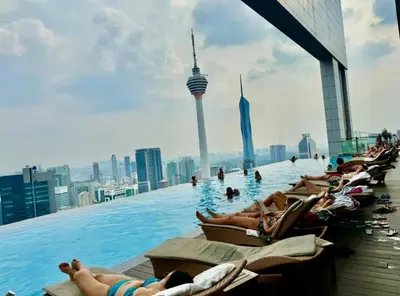 a pool on the top of a building with people laying in chairs at The Platinum KLCC By Classy in Kuala Lumpur