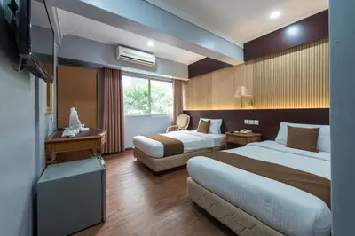 a hotel room with two beds and a television at Grand Orchard Hotel Premier in Kuala Lumpur