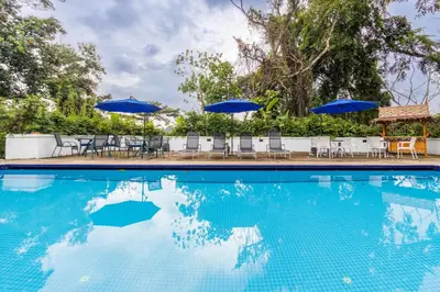 a swimming pool with chairs and blue umbrellas at Bangsar Villa for groups, event space and family fun in Kuala Lumpur