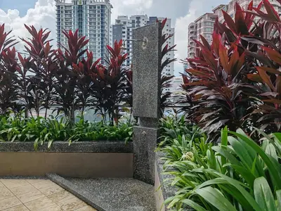 a stone pillar in a garden with plants and buildings at No Other Fee #Swiss Garden Residences by The Boston House #Bukit Bintang in Kuala Lumpur