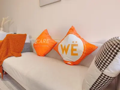 two orange pillows on a white couch with the words we at The Ovation - Bangsar Trade Centre in Kuala Lumpur