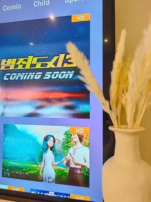 a television screen with a movie on it next to a vase at The Ovation - Bangsar Trade Centre in Kuala Lumpur