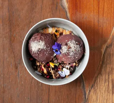 a bowl of food with two donuts and a purple flower at Societe Hartamas in Kuala Lumpur