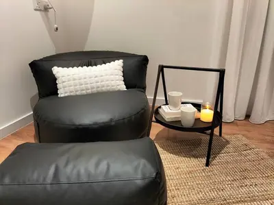 a black chair with a white pillow and a table at Quill Residence by Cozy Simple Stay in Kuala Lumpur