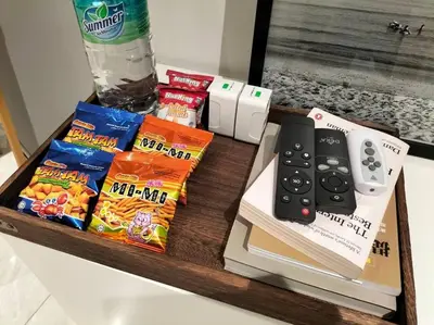 a table with a remote control and snacks on it at Quill Residence by Cozy Simple Stay in Kuala Lumpur