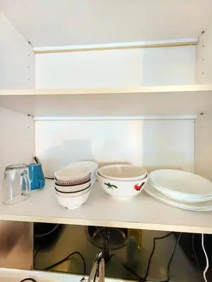 a shelf with plates and bowls on it at Summer Suites KLCC By GRAND CENTRAL in Kuala Lumpur