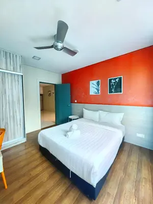 a bedroom with a large white bed with a red wall at Summer Suites KLCC By GRAND CENTRAL in Kuala Lumpur
