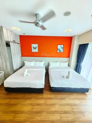 two beds in a room with an orange wall at Summer Suites KLCC By GRAND CENTRAL in Kuala Lumpur