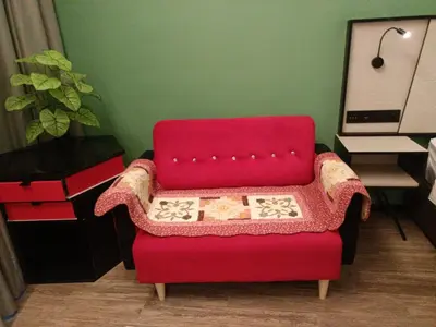 a red chair sitting in a room with a plant at James' Studio unit Maison 101 at Heritage Row, Kuala Lumpur in Kuala Lumpur