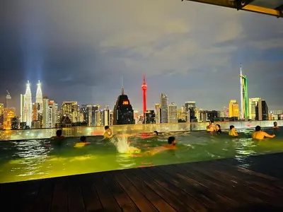 a group of people in a pool with a city in the background at Spritz Empire Regalia Suites & Residence in Kuala Lumpur