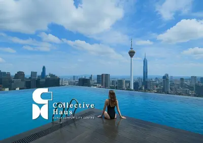 a woman sitting on the edge of a pool overlooking a city at The Platinum 2 Kuala Lumpur By Collective Haus in Kuala Lumpur