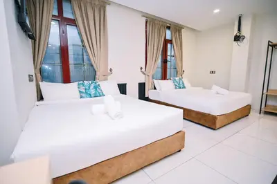 two beds in a room with white walls and windows at Swing & Pillows - Central Market Kuala Lumpur in Kuala Lumpur