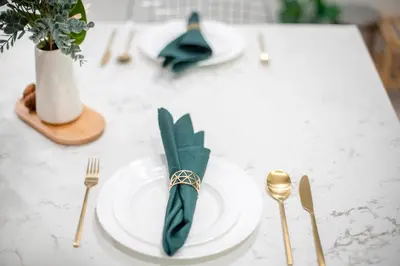 a table with a white plate with a green napkin at Novo Ampang by COBNB near Gleneagles in Kuala Lumpur