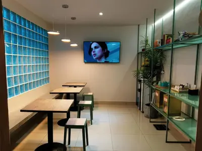 a restaurant with tables and a tv on the wall at Living At DSulaiman Hotel in Kuala Lumpur
