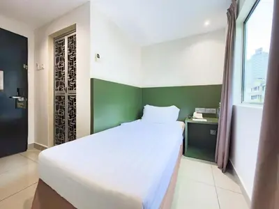 a bedroom with a white bed and a green wall at Living At DSulaiman Hotel in Kuala Lumpur