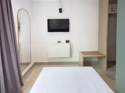 a room with a bed and a tv on a wall at Living At DSulaiman Hotel in Kuala Lumpur