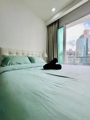 a woman laying on a large bed with a window at Bintang Suites Kuala Lumpur City Centre in Kuala Lumpur