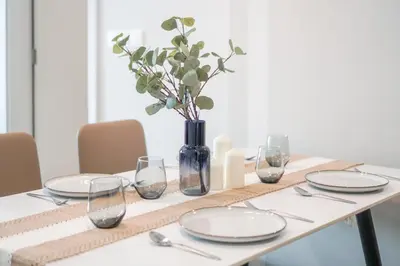 a table with plates and glasses and a vase with flowers at Datum Jelatek Residence by Airhost in Kuala Lumpur