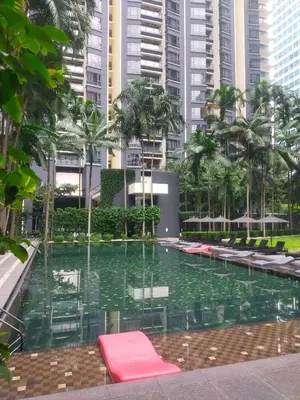 a pool with chairs and palm trees and buildings at Cosy Apartment at St Mary KL City Centre in Kuala Lumpur