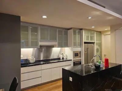 a kitchen with white cabinets and a black counter top at Cosy Apartment at St Mary KL City Centre in Kuala Lumpur