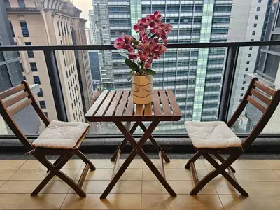 a table with a vase of flowers on a balcony at Cosy Apartment at St Mary KL City Centre in Kuala Lumpur